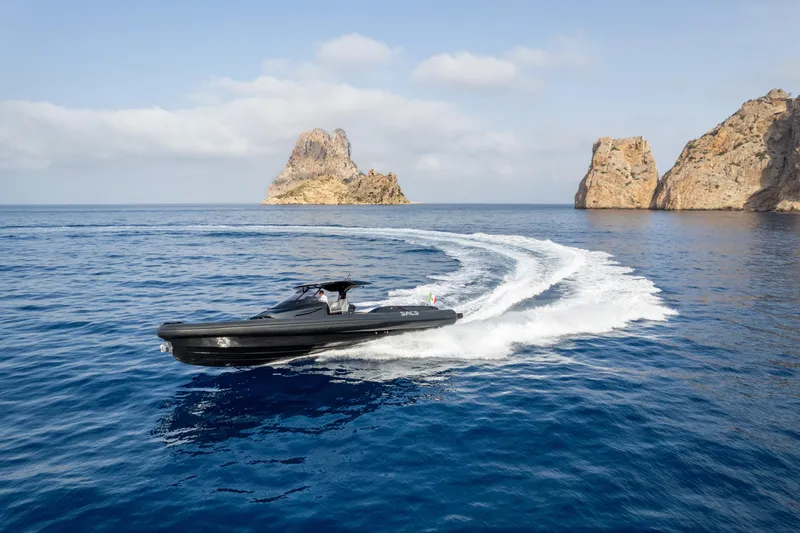  Yacht Photos Pics 2024 SACS Strider 15 cruising in clear blue waters near rocky islands.