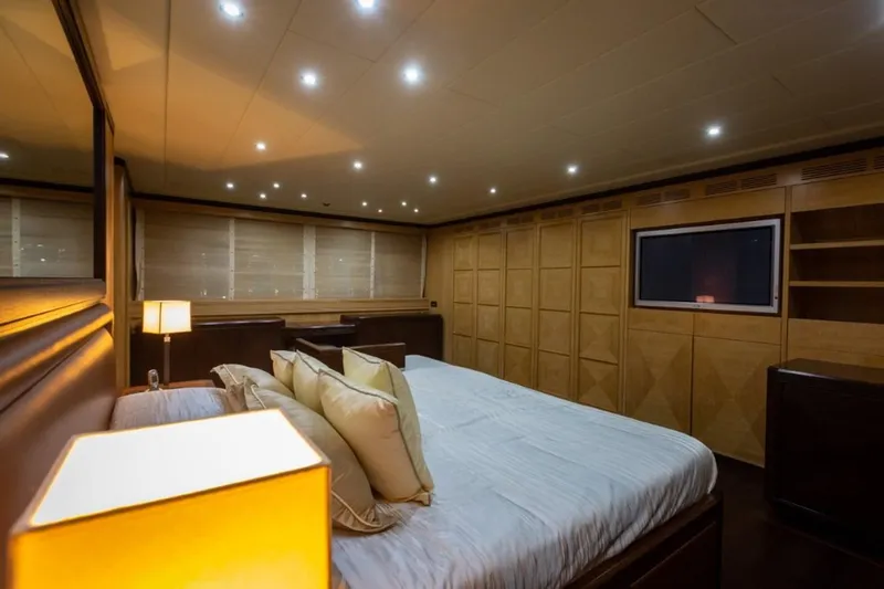  Yacht Photos Pics Luxurious bedroom interior on 2004 Mangusta 108 yacht, featuring elegant lighting and wood paneling.