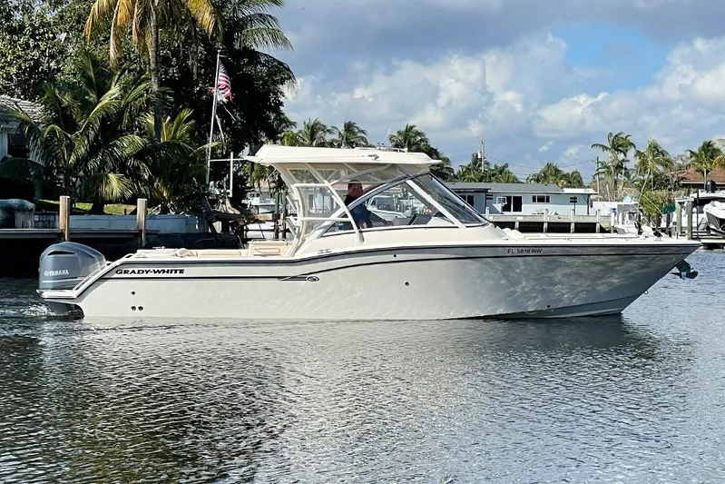  Yacht Photos Pics 2019 Grady-White Freedom 325 boat on calm water, surrounded by palm trees and docks.