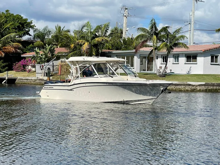  Yacht Photos Pics 2019 Grady-White Freedom 325 boat cruising on a calm waterway near waterfront homes.