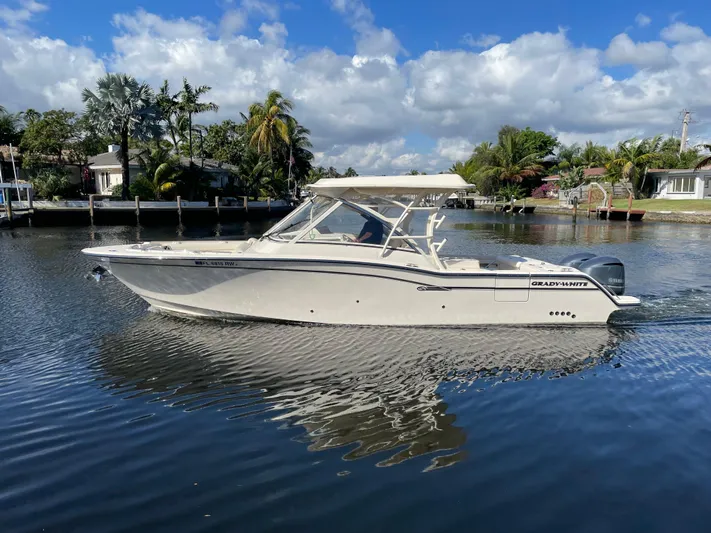  Yacht Photos Pics 2019 Grady-White Freedom 325 boat on calm water, surrounded by lush greenery and blue sky.