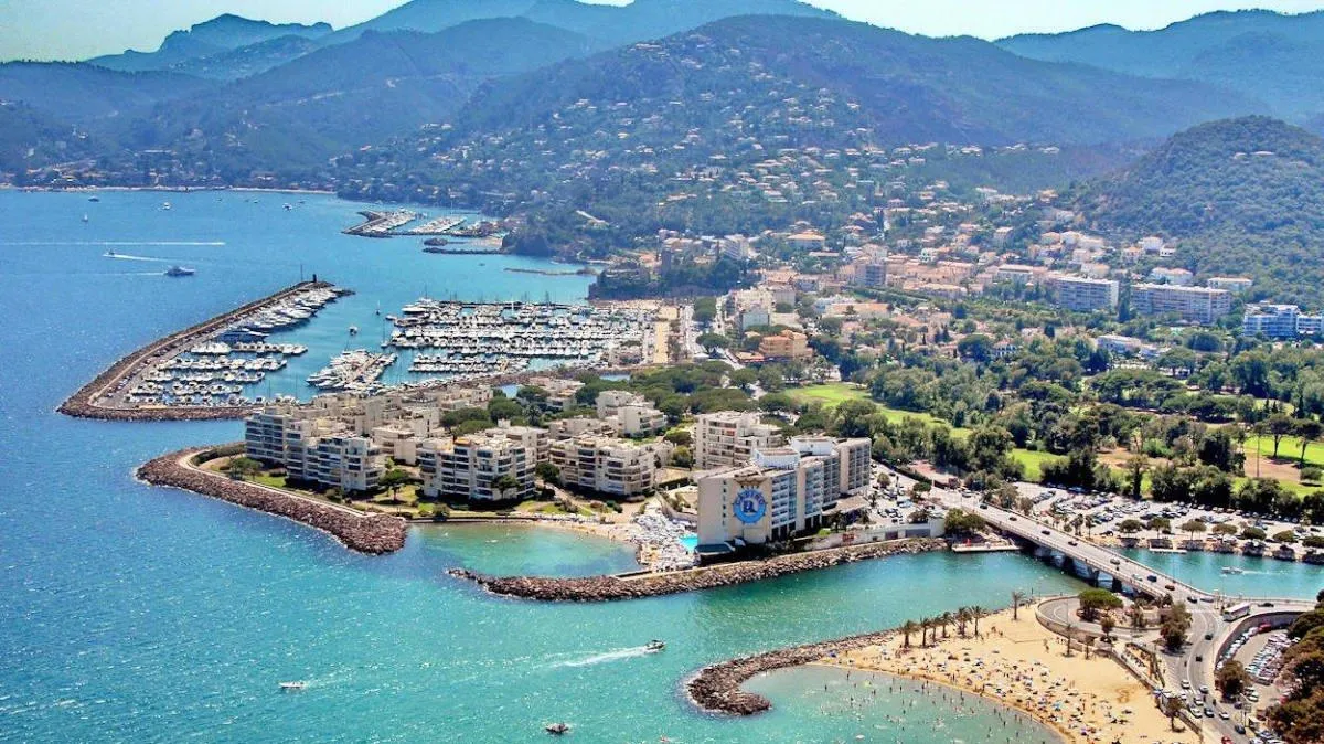 Aerial view of coastal cityscape with marina, beach, and mountains, 2023.