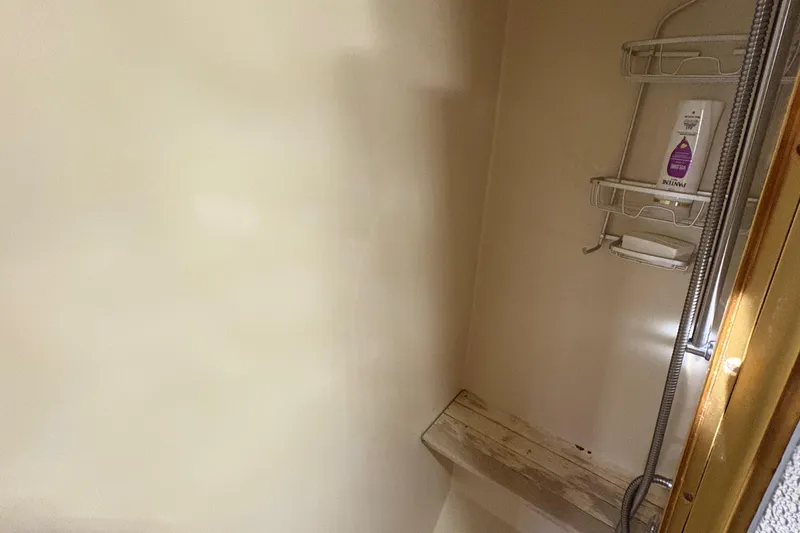 Monkey Business Yacht Photos Pics Shower area inside 1988 Egg Harbor 37 Convertible boat, featuring a wooden bench and metal shelving.