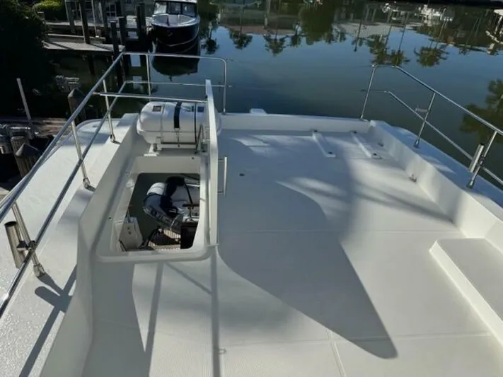 Candy Girl Yacht Photos Pics 2017 Beneteau Swift Trawler 50 deck with open hatch, docked by calm waters.