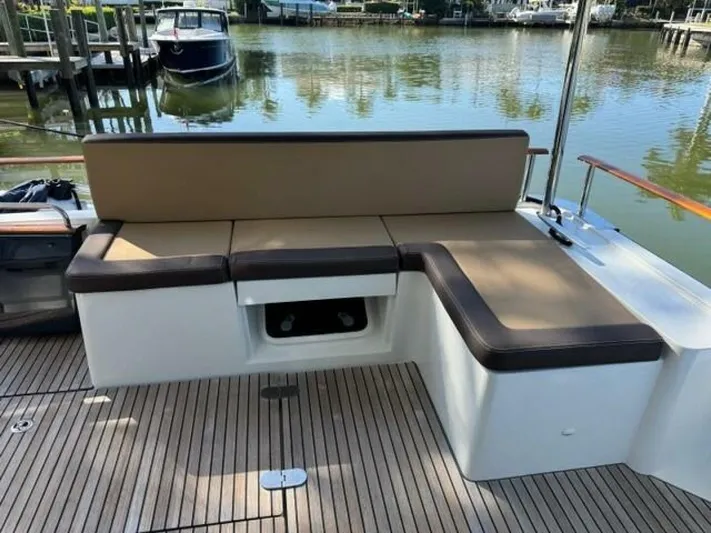 Candy Girl Yacht Photos Pics 2017 Beneteau Swift Trawler 50 deck with cushioned seating, docked by a serene waterfront.