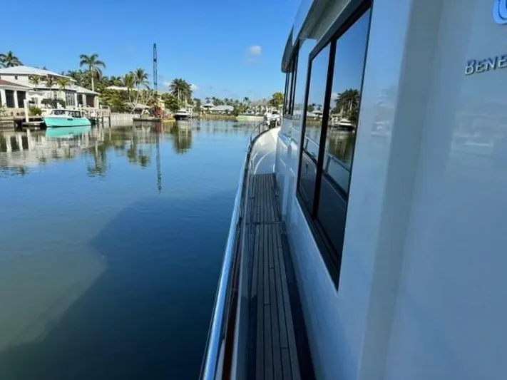 Candy Girl Yacht Photos Pics 2017 Beneteau Swift Trawler 50 on calm waterway, surrounded by palm trees and waterfront homes.