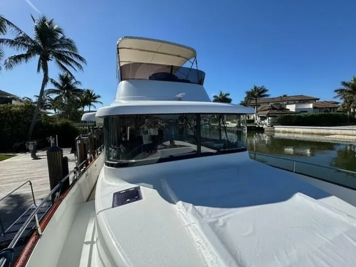 Candy Girl Yacht Photos Pics 2017 Beneteau Swift Trawler 50 docked, surrounded by palm trees and clear blue sky.