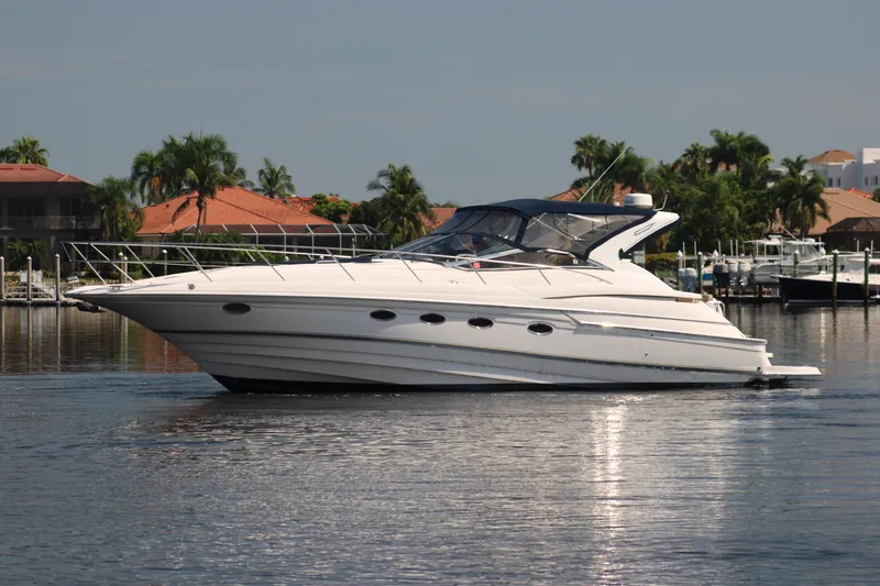 Long Overdue Yacht Photos Pics 2002 Regal Commodore 4260 yacht cruising on a calm waterway with palm trees in the background.