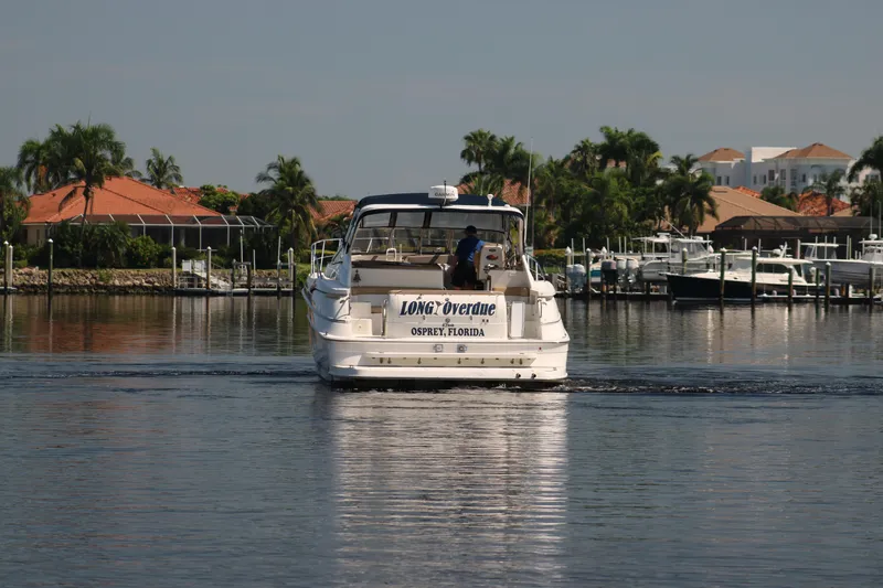Long Overdue Yacht Photos Pics 2002 Regal Commodore 4260 yacht cruising in a scenic marina with palm trees.