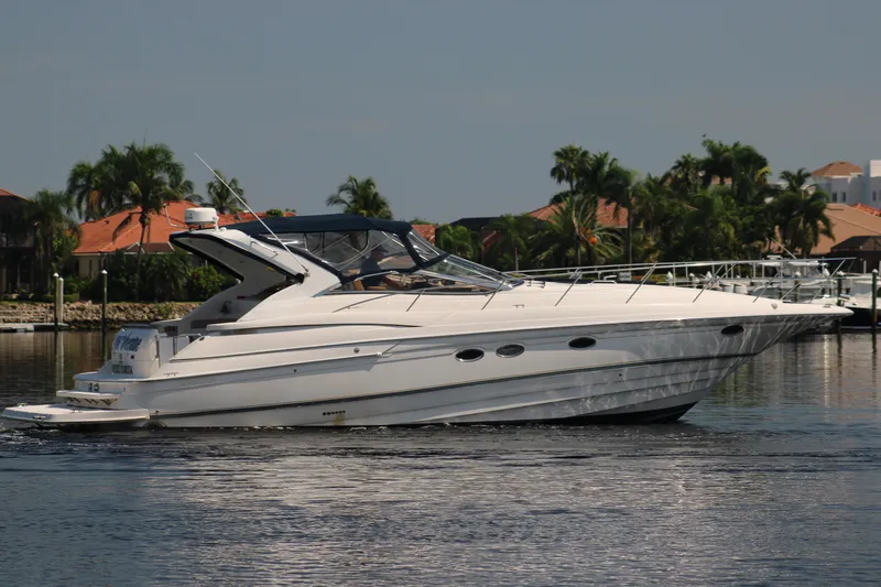 Long Overdue Yacht Photos Pics 2002 Regal Commodore 4260 yacht cruising on a sunny day near waterfront homes.