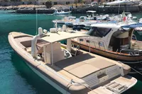 Maxi Custom Tender 1996 boat docked in scenic marina with clear turquoise water.