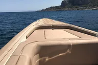 Maxi Custom Tender 1996 cruising on blue sea near rocky coastline.