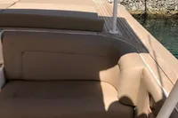 1996 Maxi Custom Tender with beige seating, docked by a stone wall.