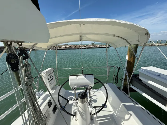 Encore Yacht Photos Pics 2011 J Boats J/95 sailboat cockpit with steering wheel, canopy, and marina view.