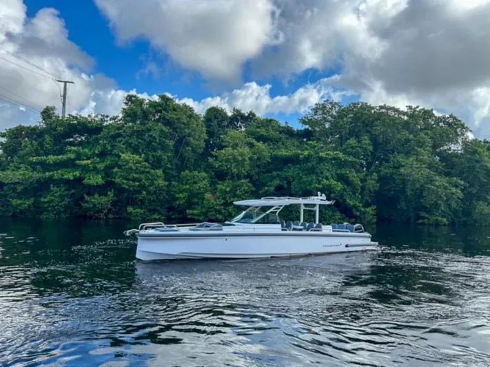  Yacht Photos Pics 2024 Axopar 37 Sun Top boat cruising on a serene waterway with lush greenery.