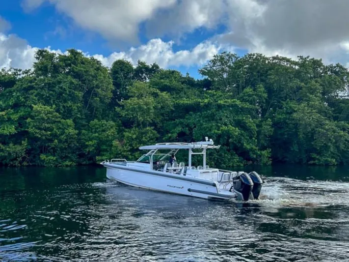  Yacht Photos Pics 2024 Axopar 37 Sun Top boat cruising on a river with lush green trees.