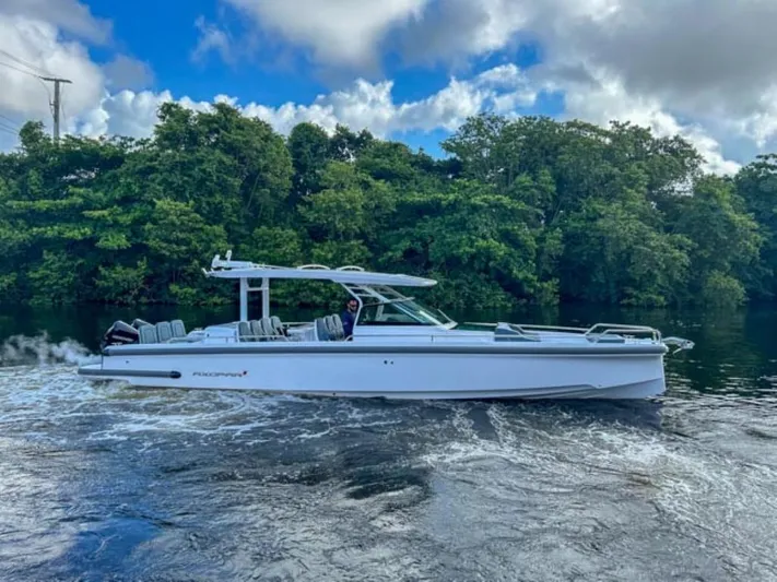  Yacht Photos Pics 2024 Axopar 37 Sun Top cruising on a river with lush green trees in the background.