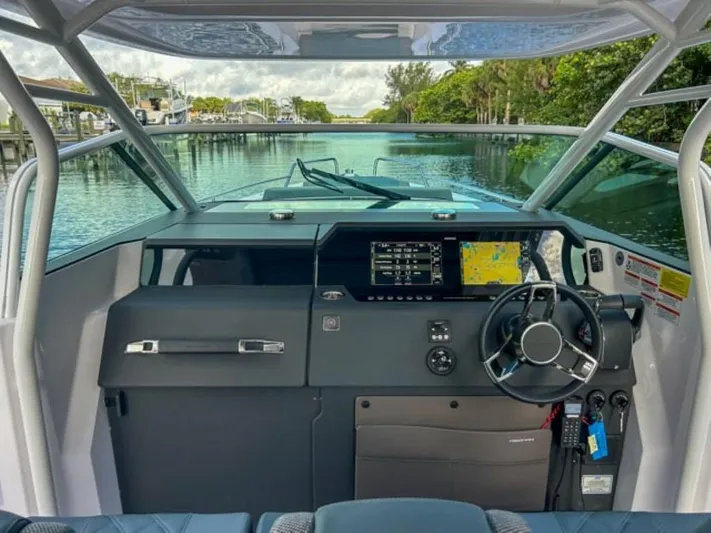  Yacht Photos Pics 2024 Axopar 37 Sun Top boat cockpit with modern navigation system and steering wheel.