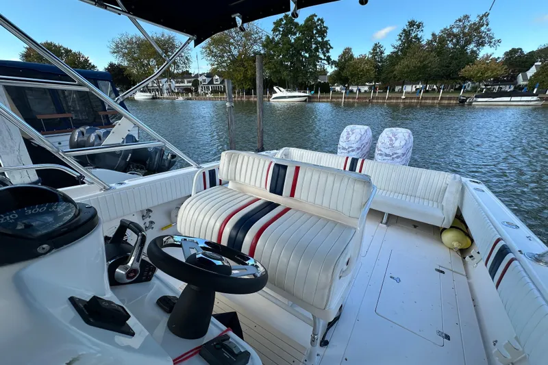  Yacht Photos Pics 1999 Intrepid 339 boat interior with striped seating, steering wheel, and waterfront view.