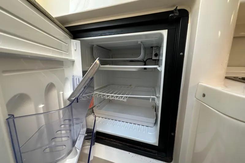  Yacht Photos Pics Open refrigerator inside a 1999 Intrepid 339 boat, showing empty shelves and compartments.