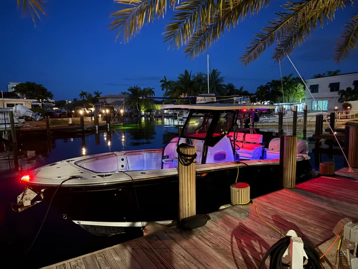  Yacht Photos Pics 2019 Blackfin 272 CC boat docked at night, illuminated with colorful lights.