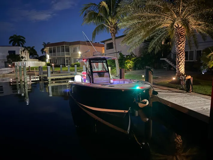  Yacht Photos Pics 2019 Blackfin 272 CC boat docked at night, surrounded by palm trees and waterfront homes.