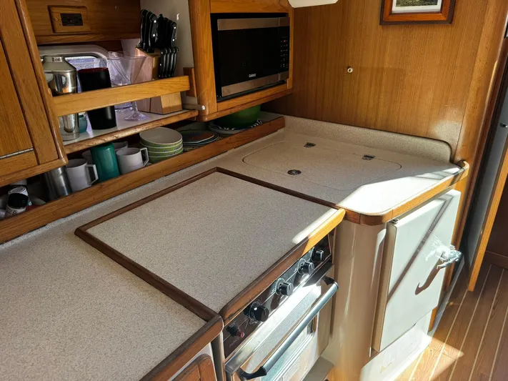J Renee Yacht Photos Pics 2004 Catalina 42 MkII yacht kitchen with stove, microwave, and wooden cabinetry.