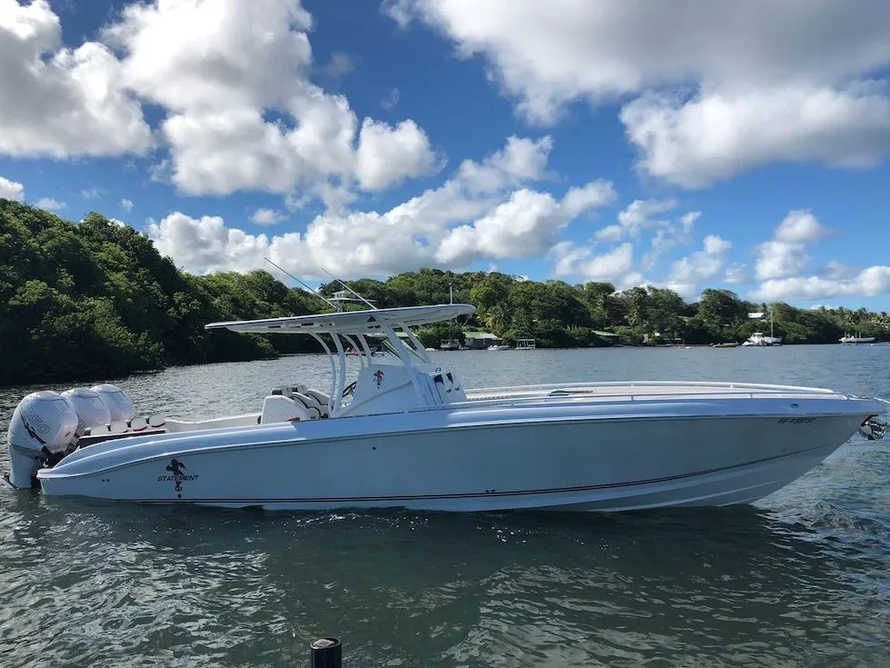 2017 Statement 380 SUV Cuddy boat on water, surrounded by lush greenery and blue sky.