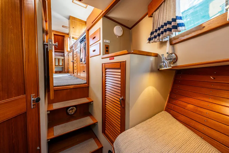Sojourn Yacht Photos Pics 1990 Grand Banks 36 Classic interior with wooden cabinetry, cozy bed, and stairs leading to the kitchen.