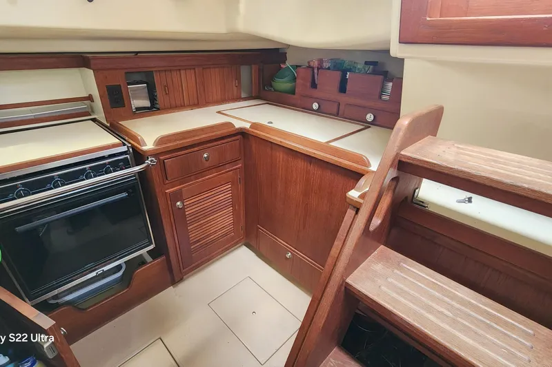 Ramble On Yacht Photos Pics Interior of 2000 Island Packet 380 sailboat kitchen with wooden cabinetry and stove.