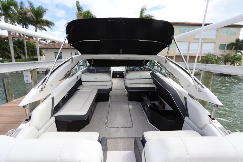  Yacht Photos Pics 2018 Regal 29 OBX boat interior with spacious seating and canopy, docked by waterfront homes.