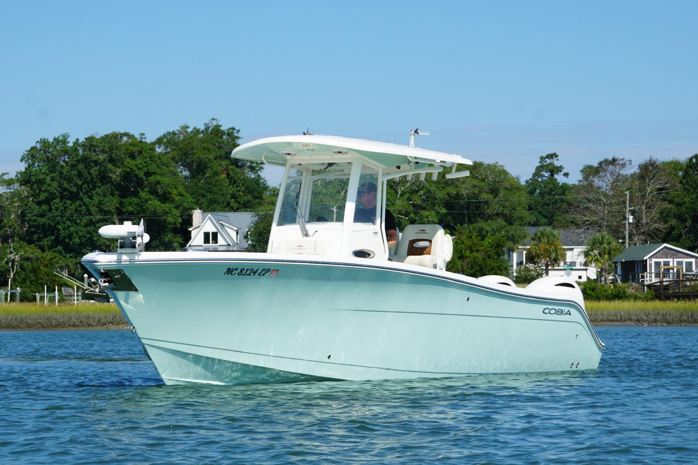 2020 Cobia 280 Center Console boat on calm water, surrounded by lush greenery.