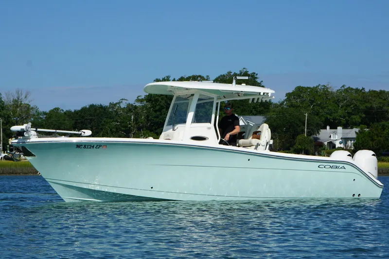 Yacht Photos Pics 2020 Cobia 280 Center Console boat on calm water, with trees in the background.