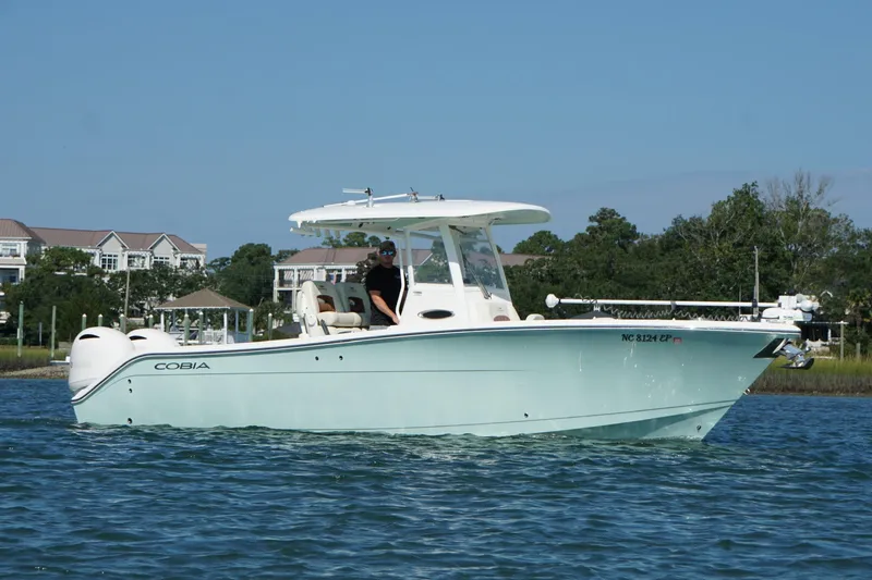  Yacht Photos Pics 2020 Cobia 280 Center Console boat cruising on a sunny day near waterfront homes.