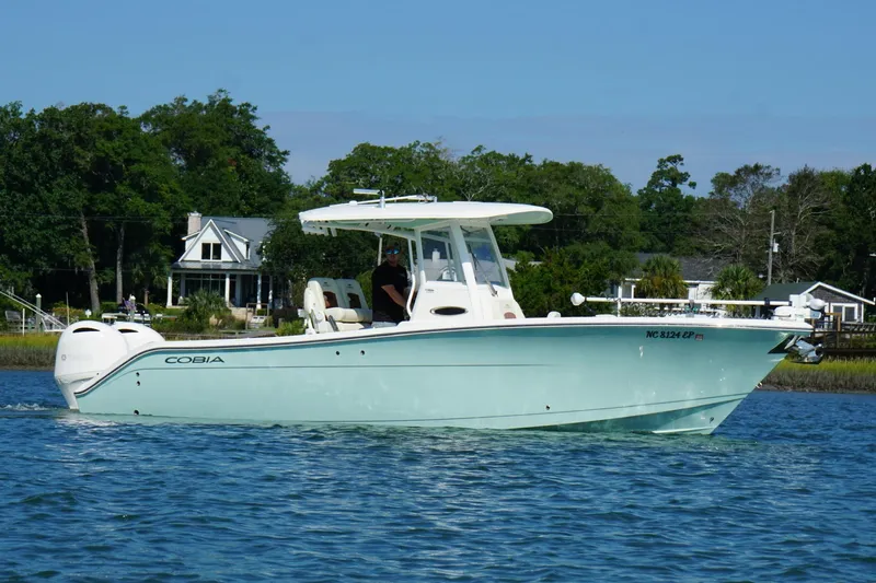  Yacht Photos Pics 2020 Cobia 280 Center Console boat cruising on a calm lake near shoreline homes.