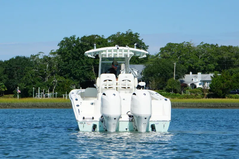  Yacht Photos Pics 2020 Cobia 280 Center Console boat on calm water, surrounded by lush greenery.