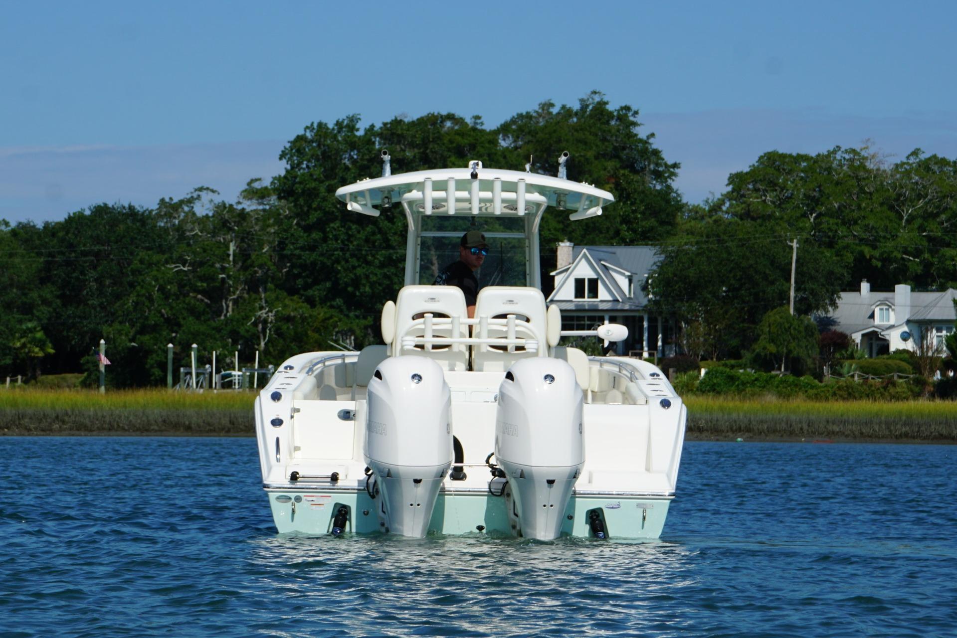 2020 Cobia 280 Center Console boat on water, with scenic shoreline background.