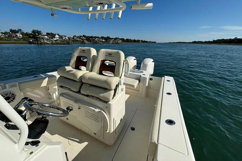  Yacht Photos Pics 2020 Cobia 280 Center Console boat on calm water, featuring comfortable seating and steering wheel.