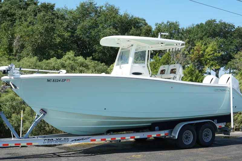  Yacht Photos Pics 2020 Cobia 280 Center Console boat on trailer, surrounded by trees.