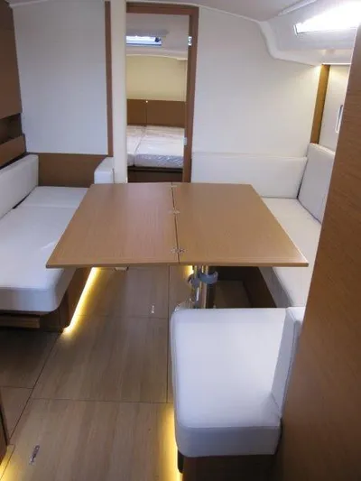 Yacht Photos Pics 2024 Jeanneau Sun Odyssey 410 interior with modern seating and wooden table.