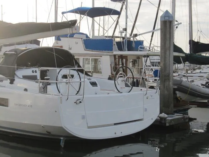  Yacht Photos Pics 2024 Jeanneau Sun Odyssey 410 sailboat docked in marina, showcasing sleek design and dual steering wheels.