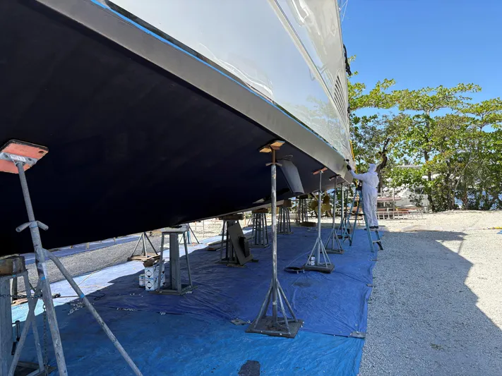  Yacht Photos Pics Person working on Buddy Davis 78 yacht hull, 2000 model, supported by stands outdoors.