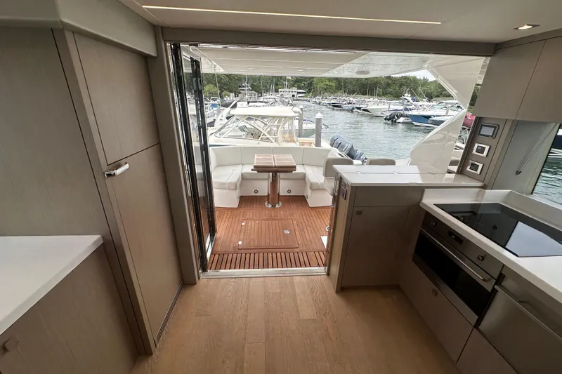  Yacht Photos Pics Interior view of 2018 Sunseeker Manhattan 52 yacht, featuring modern kitchen and outdoor seating area.
