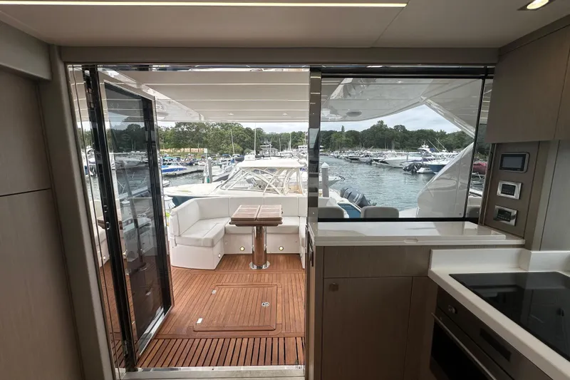  Yacht Photos Pics Interior view of 2018 Sunseeker Manhattan 52 yacht, featuring modern kitchen and outdoor seating area.