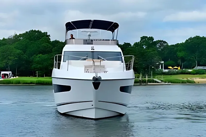  Yacht Photos Pics 2018 Sunseeker Manhattan 52 yacht on calm water, surrounded by lush greenery.