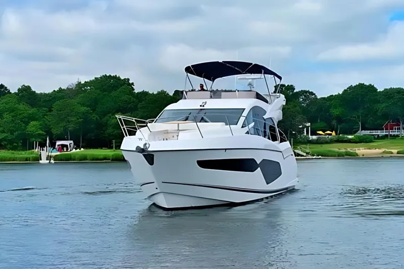  Yacht Photos Pics 2018 Sunseeker Manhattan 52 yacht cruising on a serene river with lush greenery.