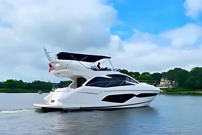  Yacht Photos Pics 2018 Sunseeker Manhattan 52 yacht cruising on a serene lake under a blue sky.