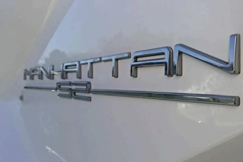  Yacht Photos Pics Close-up of 2018 Sunseeker Manhattan 52 yacht emblem on white surface.