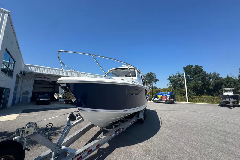  Yacht Photos Pics 2020 Pursuit OS 325 Offshore boat on trailer outside dealership under clear blue sky.