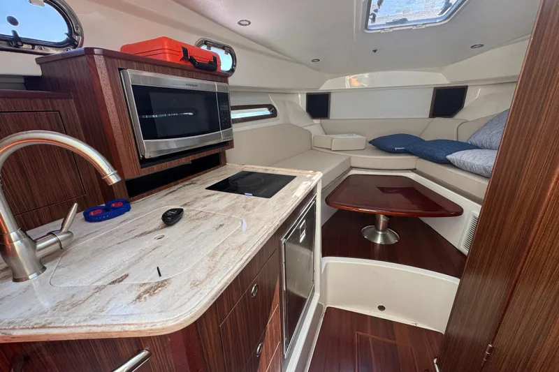  Yacht Photos Pics 2020 Pursuit OS 325 Offshore cabin interior with kitchenette and seating area.